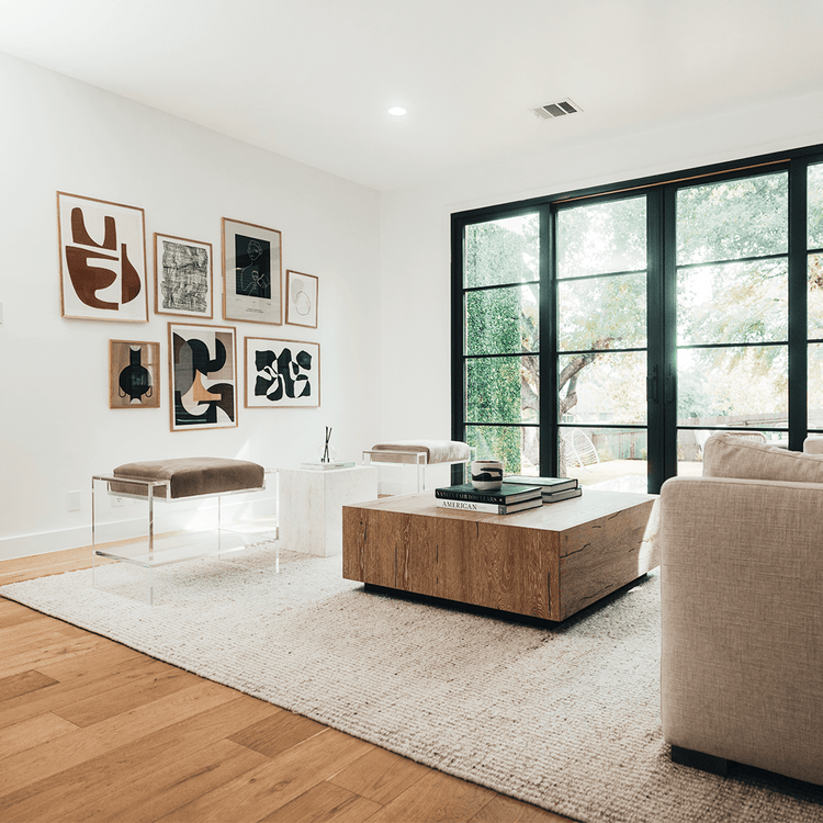 Two clear acrylic benches with brown cushions and storage shelf underneath, placed as extra seating in a modern living room with abstract art on the walls.