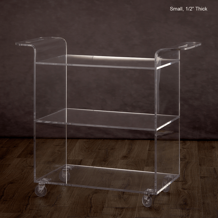 Catalog view of a clear acrylic bar cart on a wooden floor with a dark background.