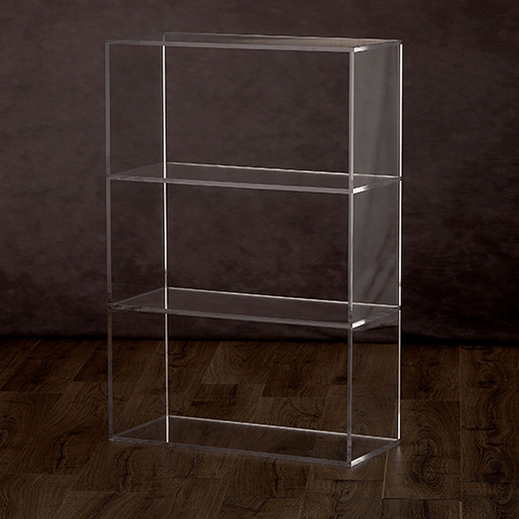 Catalog view of a clear acrylic vertical bookshelf with 3 interior shelves on a hardwood floor.