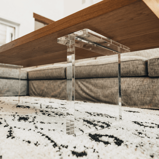 A closeup of acrylic lucite panel table legs under a wooden coffee table available for purchase to add to any existing tabletop.