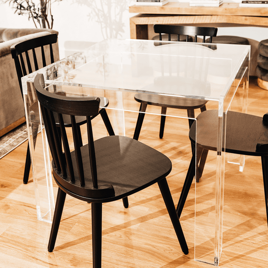 A closeup view of a square clear acrylic lucite game table featuring a chair on each side in a living room.