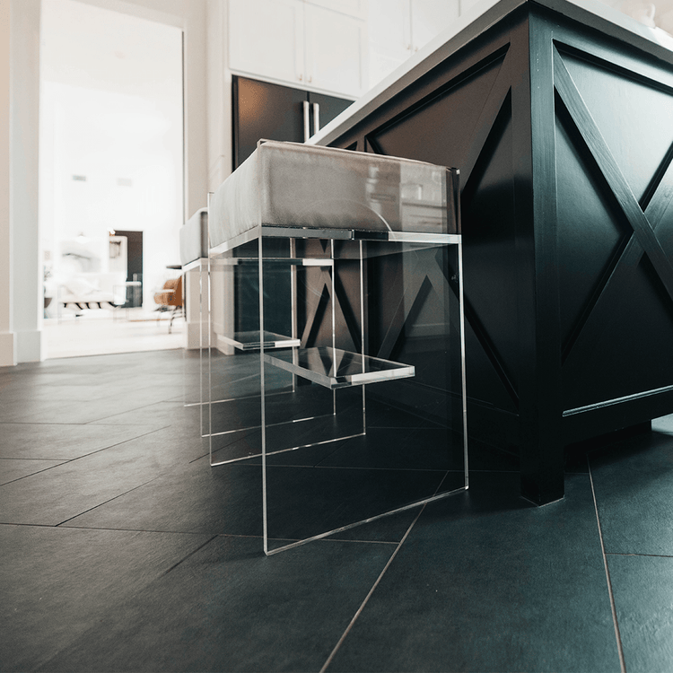 A set of two clear acrylic modern bar stools with white upholstered seats and clear acrylic legs, positioned at a kitchen island.