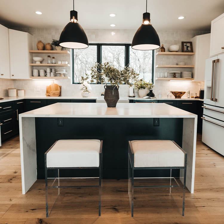 A set of two clear acrylic modern bar stools with white upholstered seats and clear acrylic legs, positioned at a kitchen island.