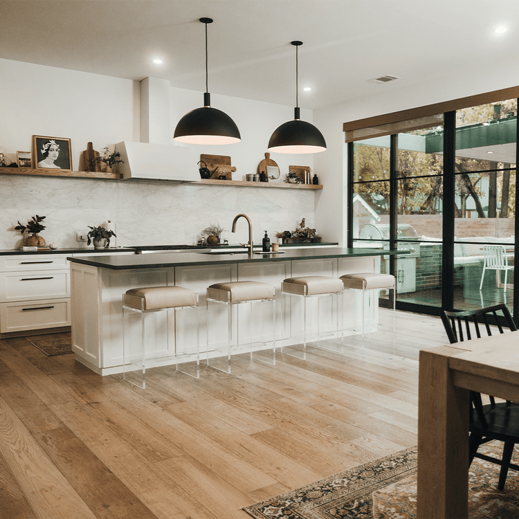 A set of four clear acrylic modern bar stools with beige upholstered seats and clear acrylic legs, positioned in a kitchen setting.