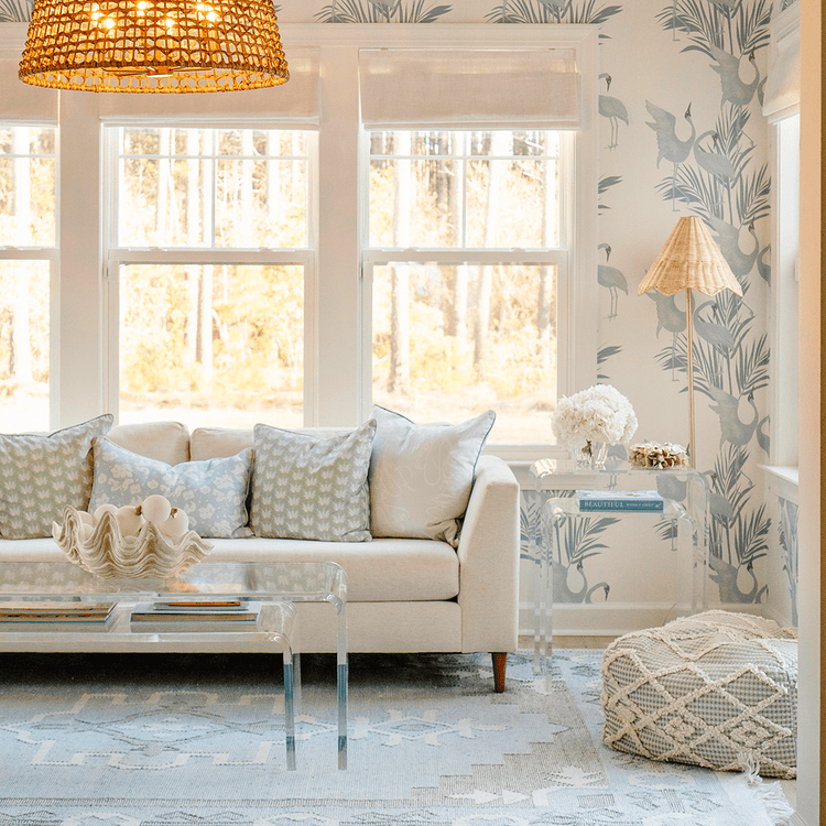 A clear acrylic nesting end table set placed beside a white sofa also featuring a nesting coffee table set placed in front of it.