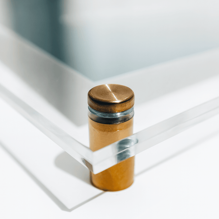 Closeup of 1 corner of a clear acrylic picture frame with gold accent hardware.