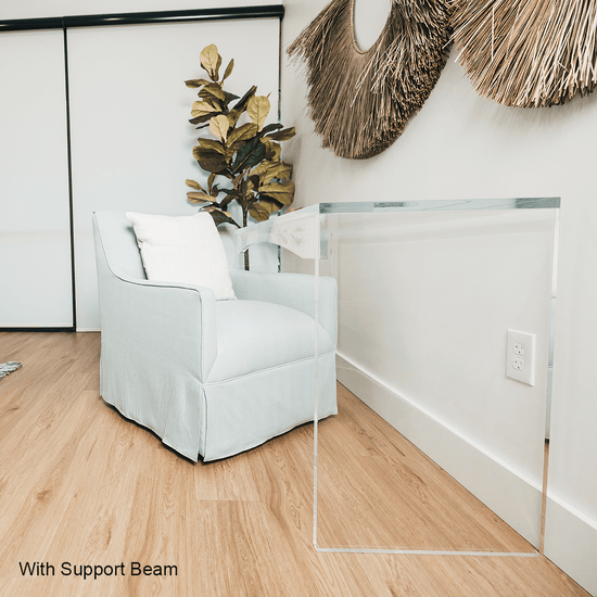 A light blue armchair slid up to a clear acrylic lucite slab desk that's against a decorated wall in a living room.