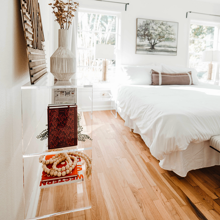 Sideview of a clear acrylic 4 cube storage unit displaying artwork, vases, books, and decor in a bedroom. The unit features 2 rows of 2 cubes.
