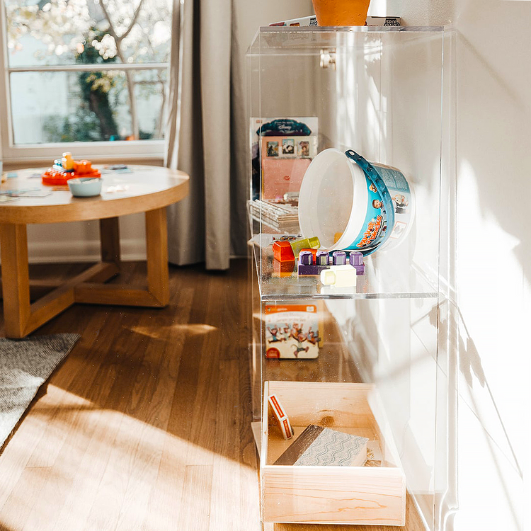 Sideview of a clear acrylic 4 cube storage unit displaying toys and books in a child's playroom. The unit features 2 rows of 2 cubes.