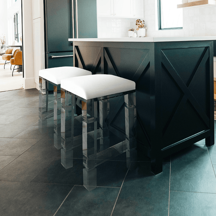 2 clear acrylic lucite barstools with white padded seats placed at a kitchen island.