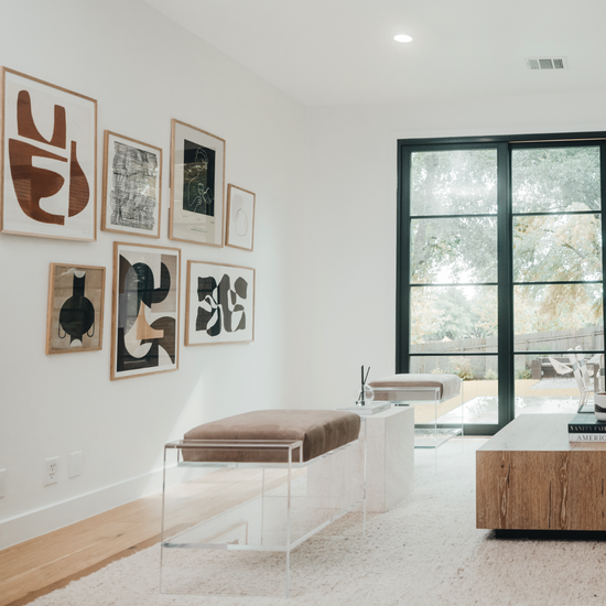 Two clear acrylic benches with brown cushions and storage shelf underneath, placed as extra seating in a modern living room with abstract art on the walls.
