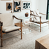 A clear acrylic side table shaped like the number 5 placed between 2 chairs in a living room.