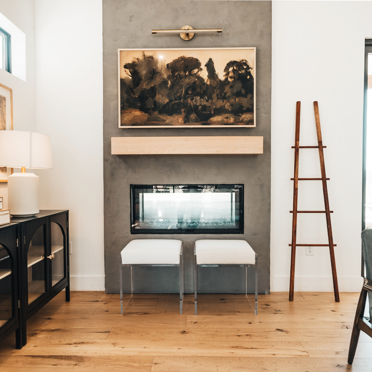 Modern living room with 2 clear acrylic accent chairs placed in front of a fireplace. 