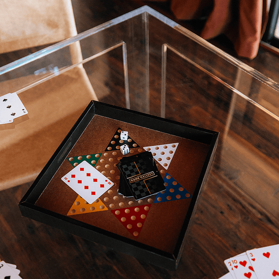 A closeup of a square clear acrylic lucite game table set up with a game board and cards.