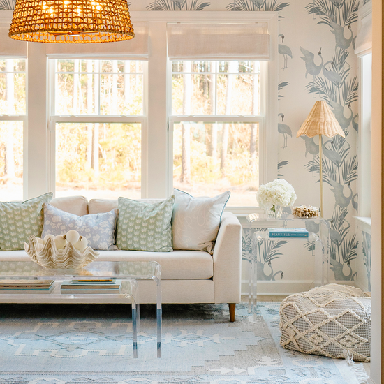 A clear acrylic nesting end table set placed beside a white sofa also featuring a nesting coffee table set placed in front of it. 