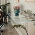 Clear acrylic lucite console table with a decorative vase and plant in a living room setting.