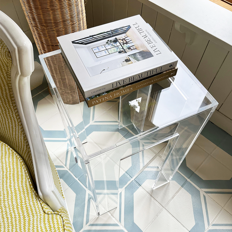 A closeup of the top of a clear acrylic side table with a square leg style base.