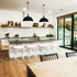 4 clear acrylic lucite barstools with white padded seats placed at a kitchen island.
