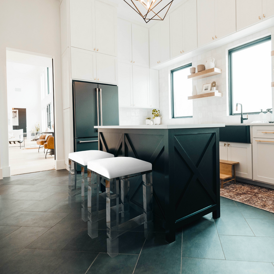  2 clear acrylic lucite barstools with white padded seats placed at a kitchen island.