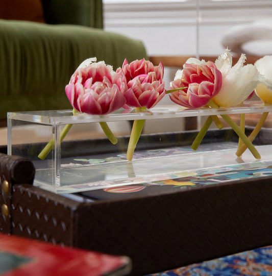 Corner closeup of a clear acrylic horizontal short stem floral centerpiece displaying fresh cut flowers.