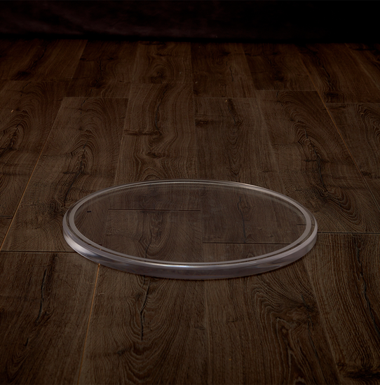 Catalog view of a clear acrylic round centerpiece tray on a hardwood table.