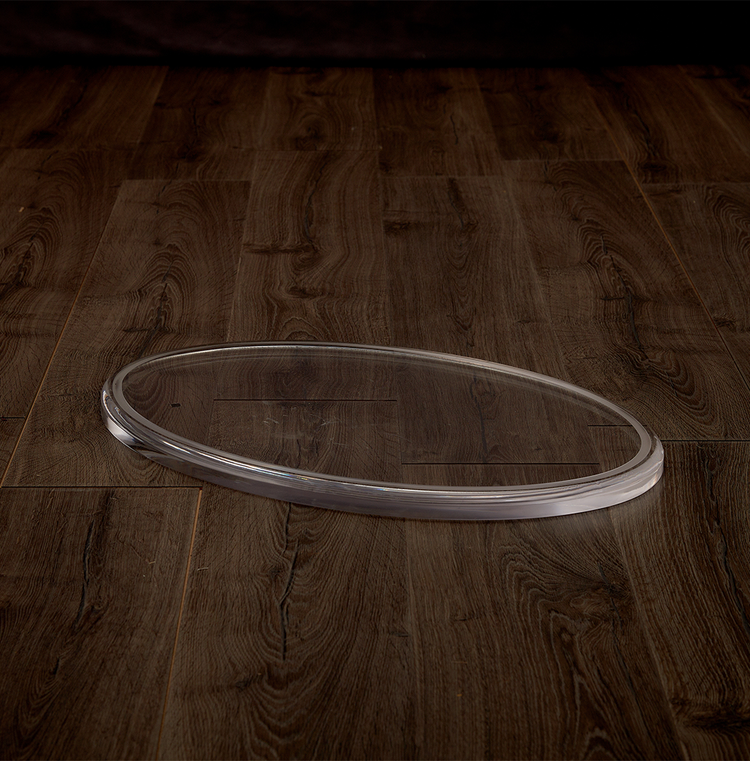 Catalog view of a clear acrylic oval centerpiece on a hardwood table.