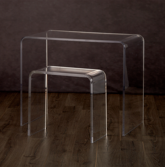 Catalog view of a clear acrylic waterfall edge vanity stool placed under a clear acrylic waterfall edge vanity on a hardwood floor.