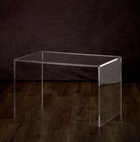 Catalog view of a clear acrylic slab desk or coffee table on a hardwood floor.