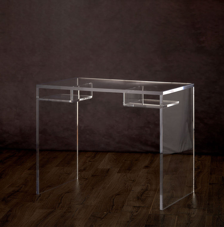 Clear acrylic slab style desk with 2 interior shelves on the left and right sides of the desk on a hardwood floor.
