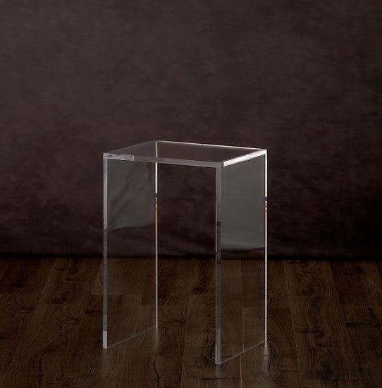 Clear acrylic end table on a hardwood floor.