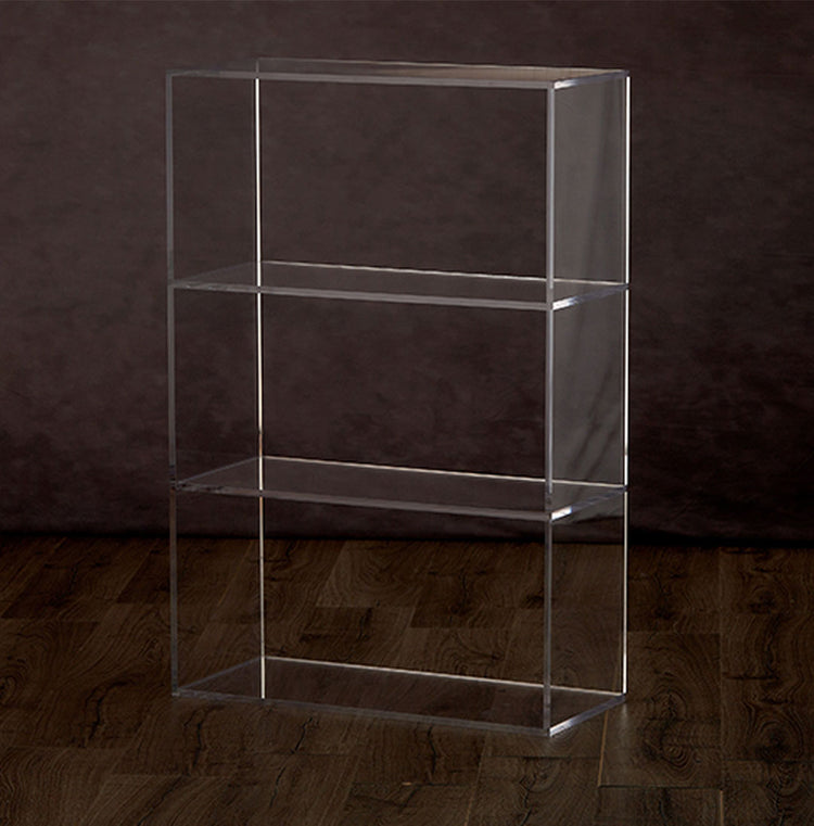 Catalog view of a clear acrylic vertical bookshelf with 3 interior shelves on a hardwood floor.
