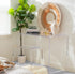 Clear acrylic waterfall edge vanity displaying books, perfumes, and art decor paired with a clear acrylic waterfall edge vanity stool placed in a bedroom.