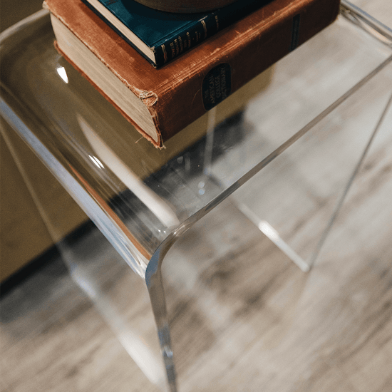Closeup of the waterfall edge on a clear acrylic end table displaying books.